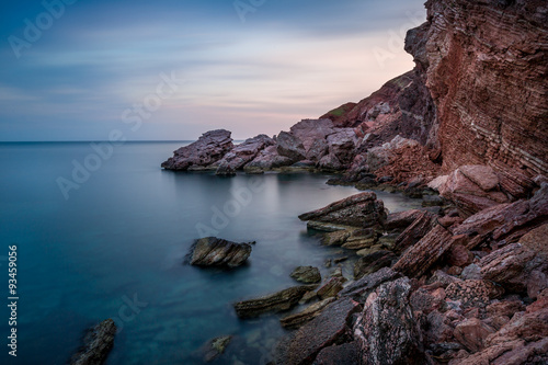 Long exposure shot of Adriatic sea coast and red rock cliff. Sutomore, Montenegro