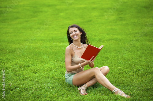 Young beautiful brunette girl reading a book outdoor