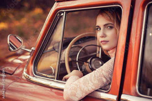 beautiful woman sitting in red retro car