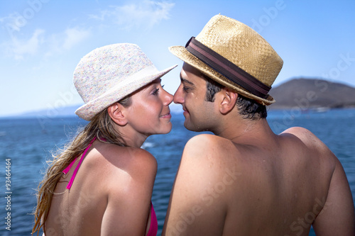 Young couple is sitting and sunbathing on a wooden port