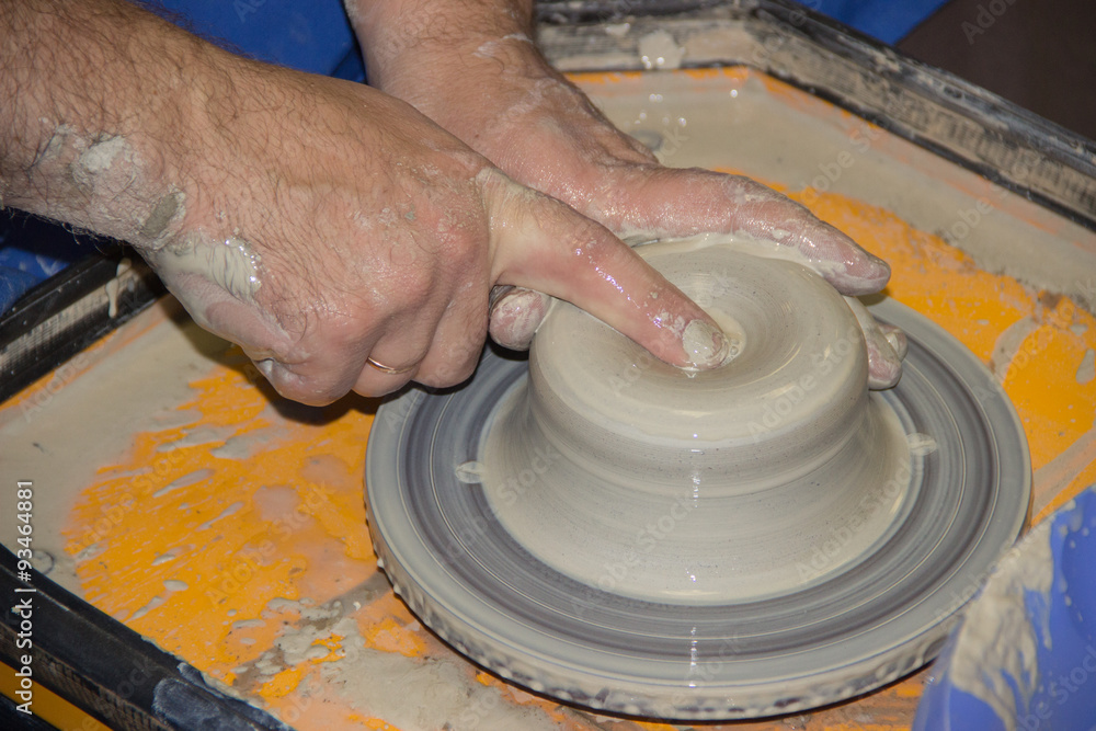 Potter makes on the pottery wheel clay jug. The hands of a potte Potter makes on the pottery wheel clay jug. The hands of a potte