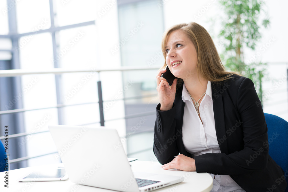Businesswoman working & sitting at her desk in an office Businesswoman working & sitting at her desk in an office