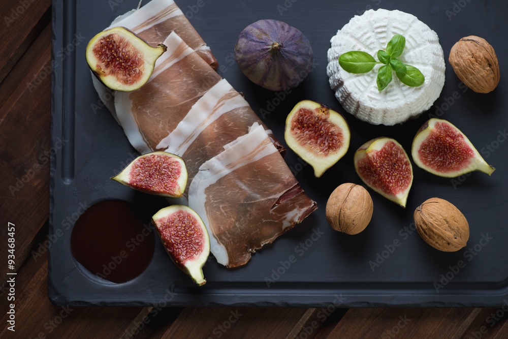 Basalt plate with ricotta, figs, ham and walnuts, above view