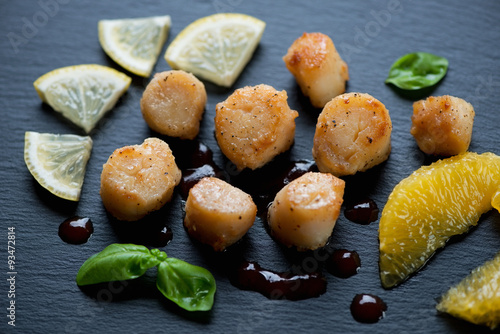 Fried scallops with orange fillet, lemon and sauce, close-up
