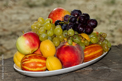 Fruits on a plate on a big old tree stump in the garden