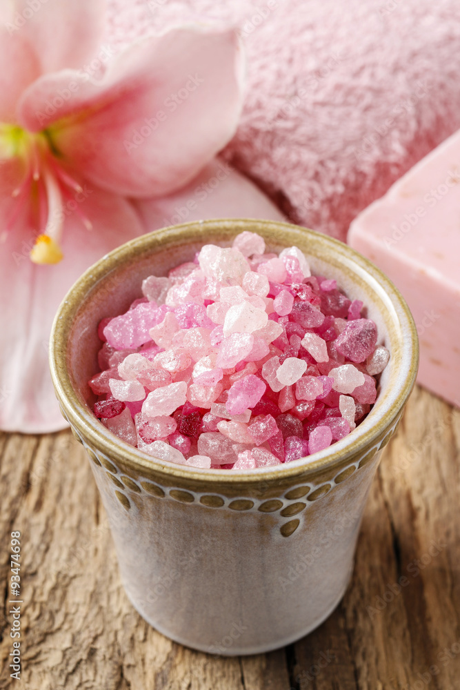 Bowl of pink sea salt and lily flower in the background Bowl of pink sea salt and lily flower in the background