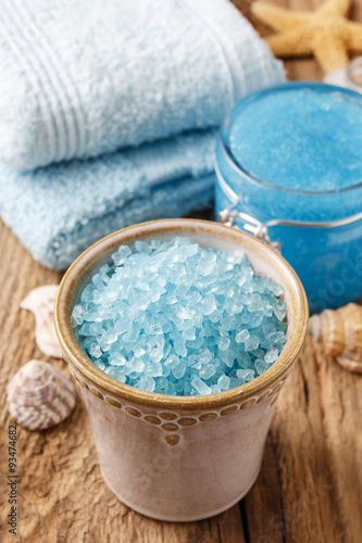 Bowl of blue sea salt and other spa cosmetics on rustic wood