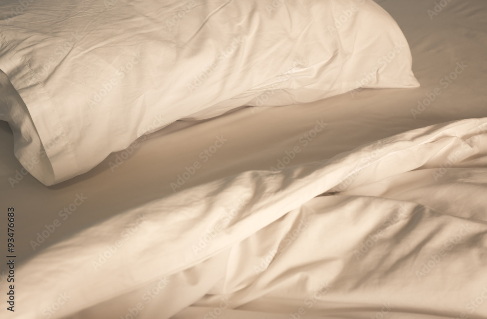 Obraz premium An unmade bed with white linens