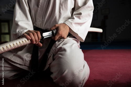 Close up of young martial arts fighter with katana siting in seiza position