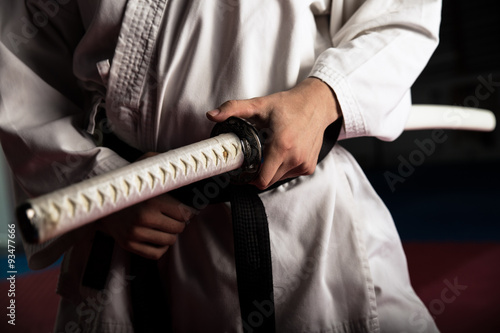 Close up of young martial arts fighter with katana siting in seiza position