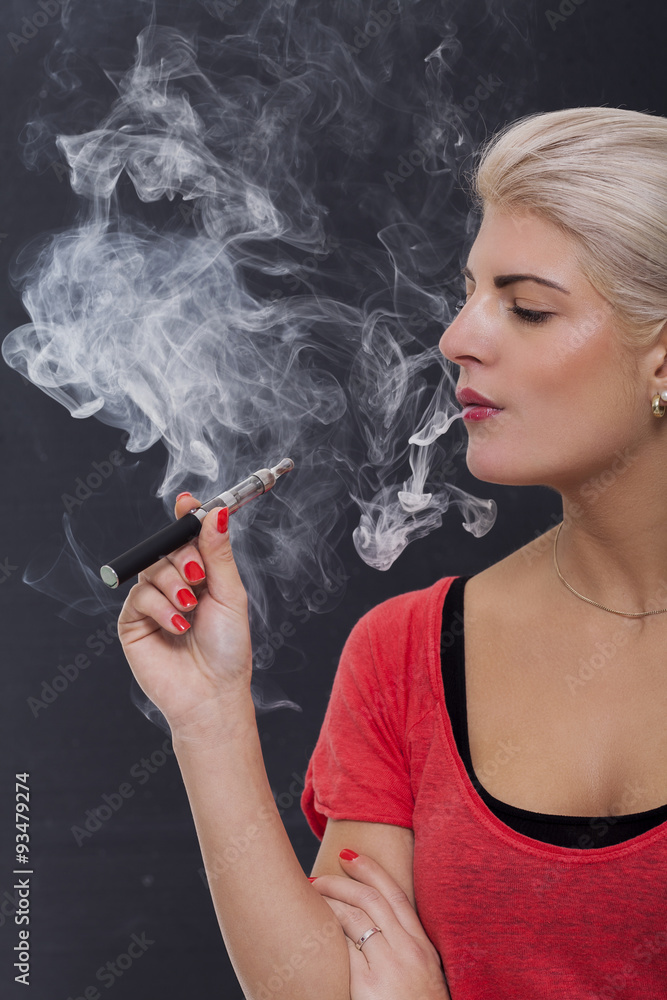Fototapeta premium Junge attraktive blonde Frau raucht eine e-zigarette