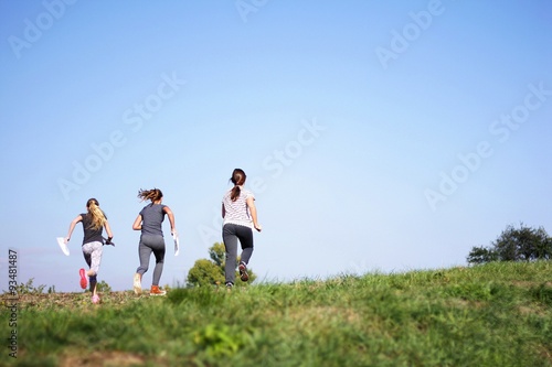 Three young girls running around the field 