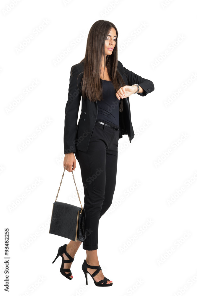 Attractive tanned business woman checking time while walking. Side view isolated Attractive tanned business woman checking time while walking. Side view isolated