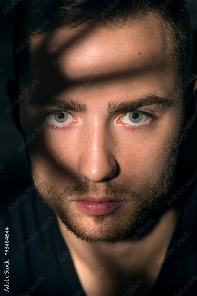 Obraz premium Young handsome man in dark shadow and ray of light