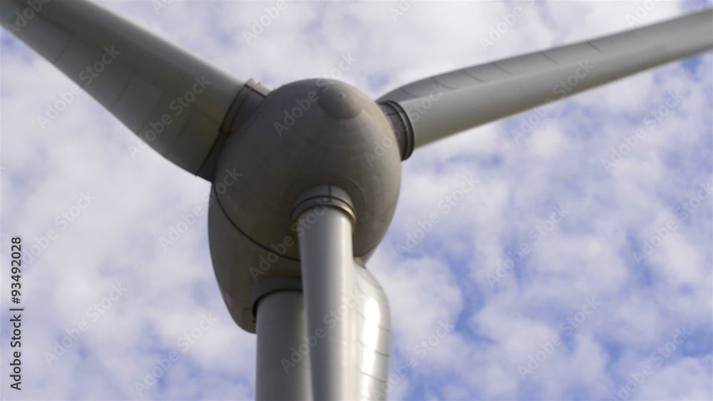 Wind turbine turning in the wind with fluffy clouds floating by in the background. Wind turbine turning in the wind with fluffy clouds floating by in the background.