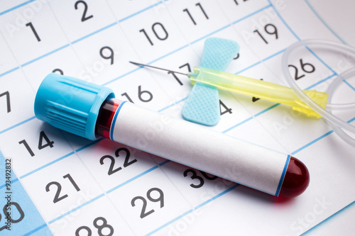 blood tube and needle on the bottom of an appointment calendar / February 2016 planning calendar and blood samples in tubes 