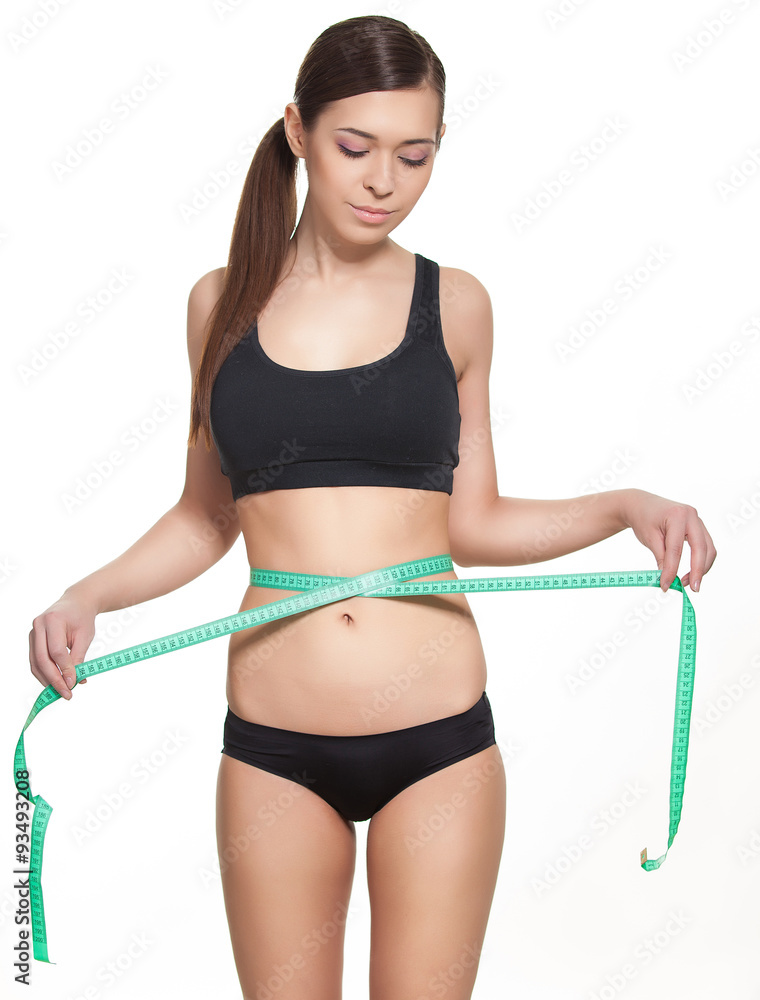 Woman measuring her waistline with a green measuring tape, isolated in white. Perfect Slim Body. Diet Woman measuring her waistline with a green measuring tape, isolated in white. Perfect Slim Body. Diet