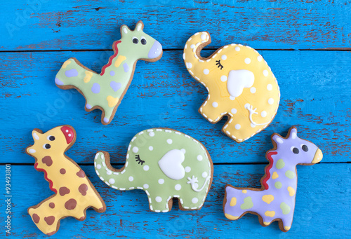 Homemade gingerbread cookie in the shape of green, red and yellow elephants and giraffes on a wooden background. Space for text and selective focus. photo