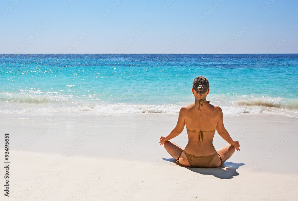 Beautiful girl in bikini sitting in lotus pose
