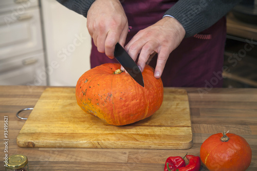 Man about to cut pumpkin.