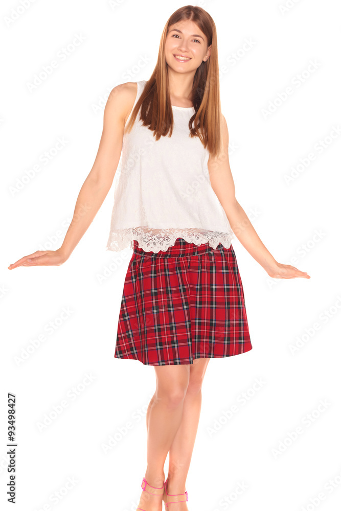 Fototapeta premium Pretty girl in a vest and skirt behind white wall