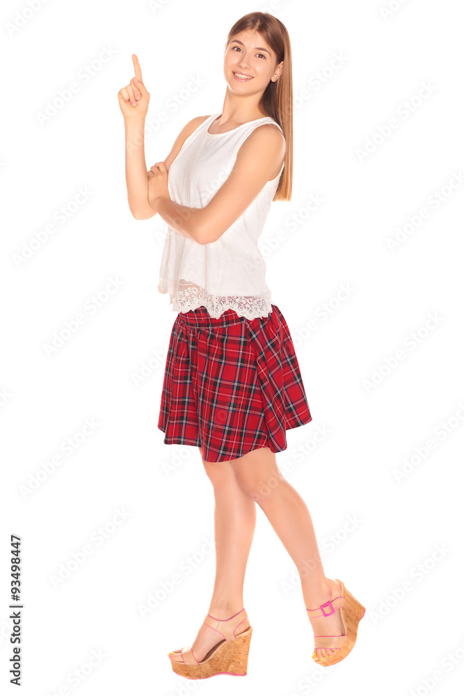 Fototapeta premium Pretty girl in a vest and skirt behind white wall