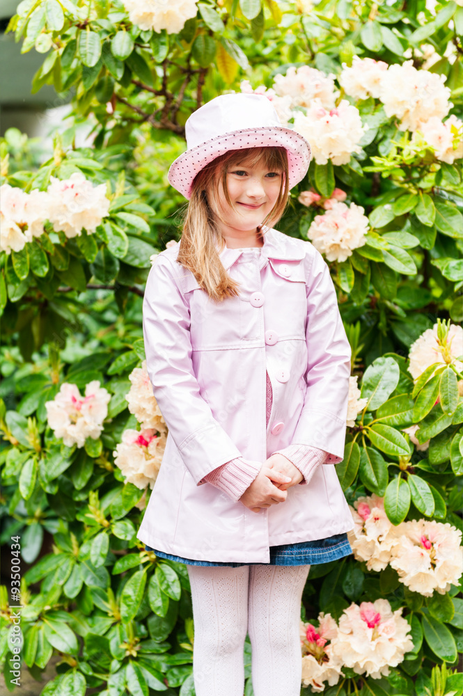 Spring portrait of adorable little girl, wearing rain hat and coat