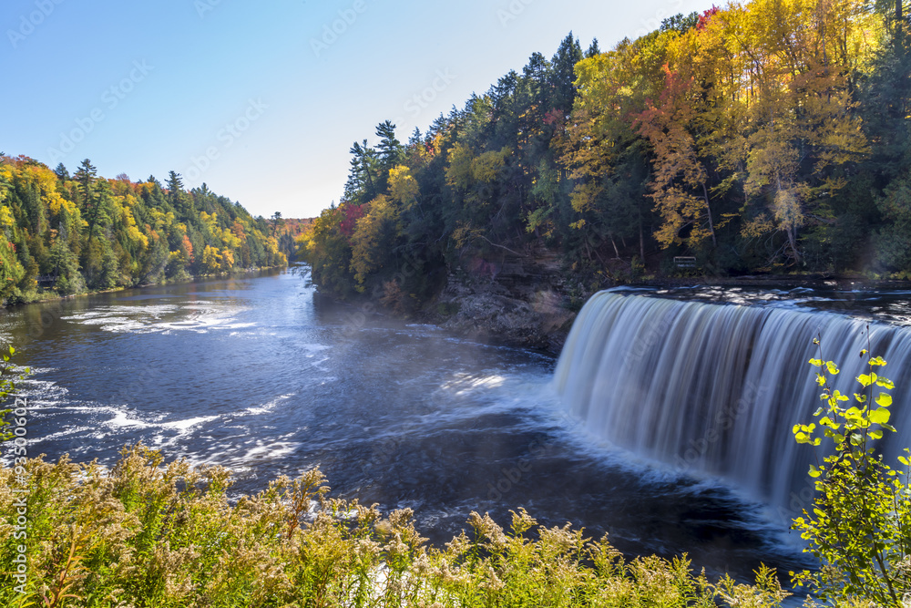 Tahquamenon Falls in Michigan's eastern Upper Peninsula seen with colorful fall foliage. This beautiful waterfall is said to be the second largest in the United States east of the Mississippi River. - obrazy, fototapety, plakaty 