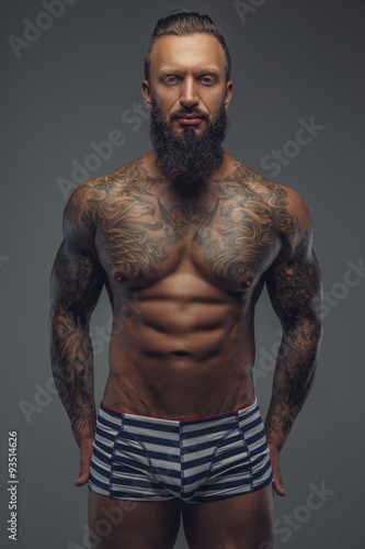 Shirtless tattooed man with beard.