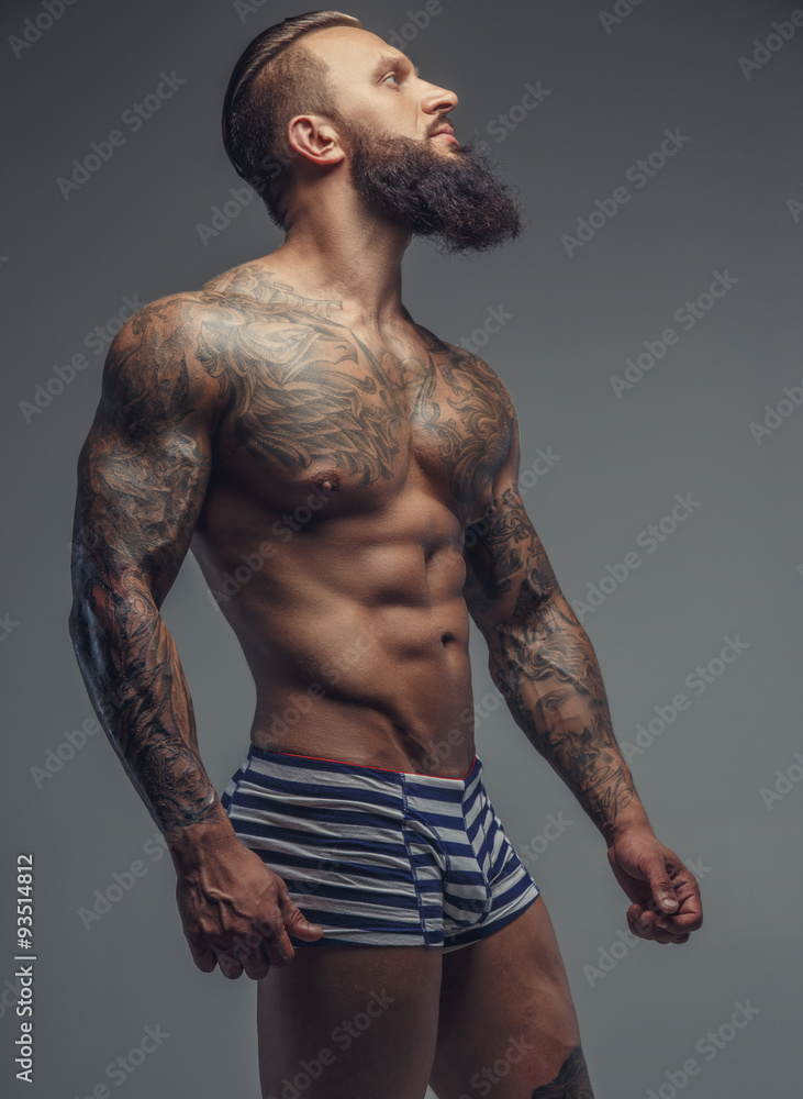 Naklejka premium Brutal tattooed man in stripes panties.