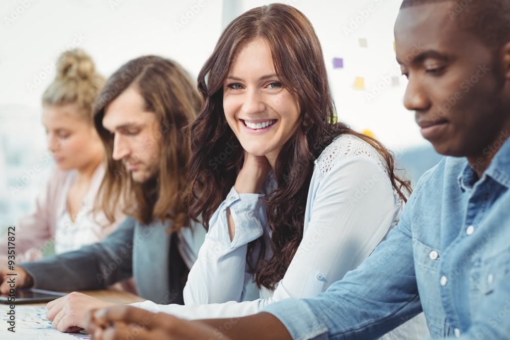 Portrait of smiling woman sitting at desk with coworkers Portrait of smiling woman sitting at desk with coworkers