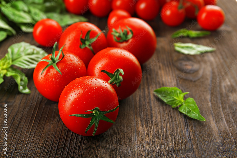 Fresh tomatoes with basil on wooden table close up Fresh tomatoes with basil on wooden table close up