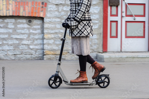 Girl in casual wear on kick scooter on street