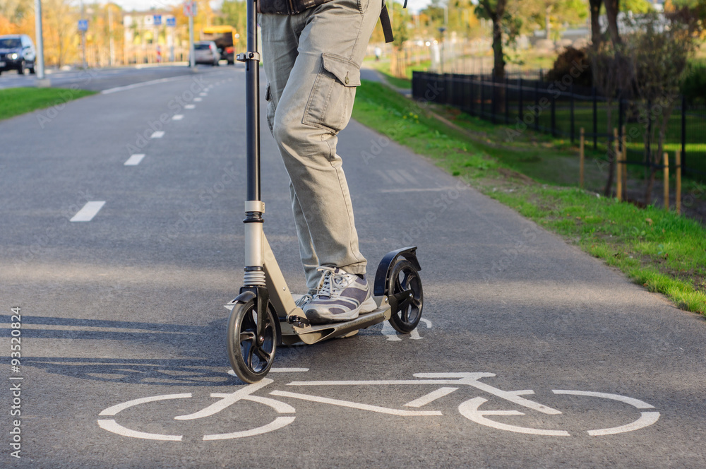 Fototapeta premium Young man in casual wear on kick scooter on street