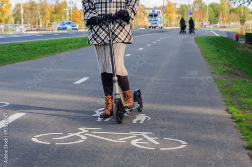 Girl in casual wear on kick scooter on street