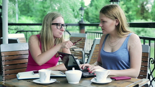 Girfriends studying and talking over laptop in cafe 
 photo