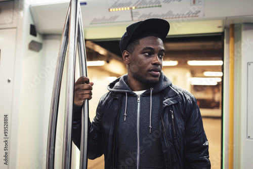 Afro man with cap standing in metro.