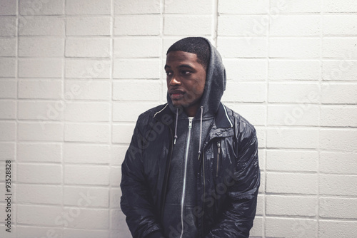 Photography Urban fashion afro man with hoody leaning against white wall.