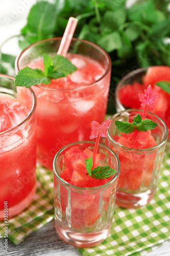 Cold watermelon desserts and drinks in glasses, on wooden table background