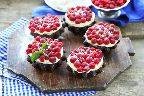 Sweet cakes with raspberries on wooden table background