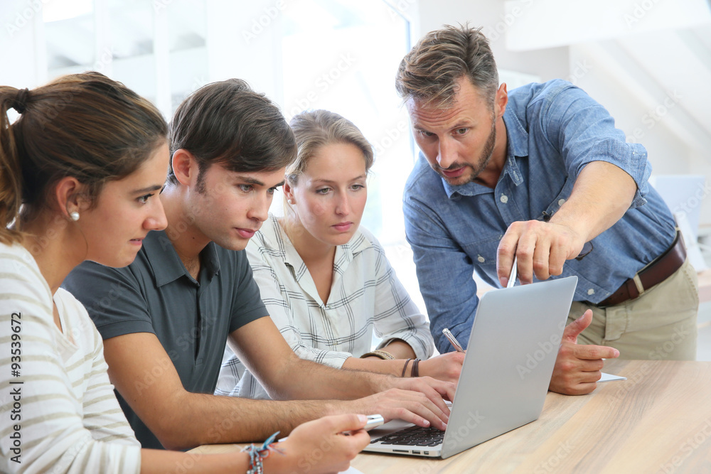 Teacher with group of students working on laptop computer