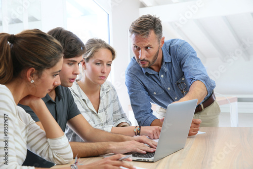 Teacher with group of students working on laptop computer