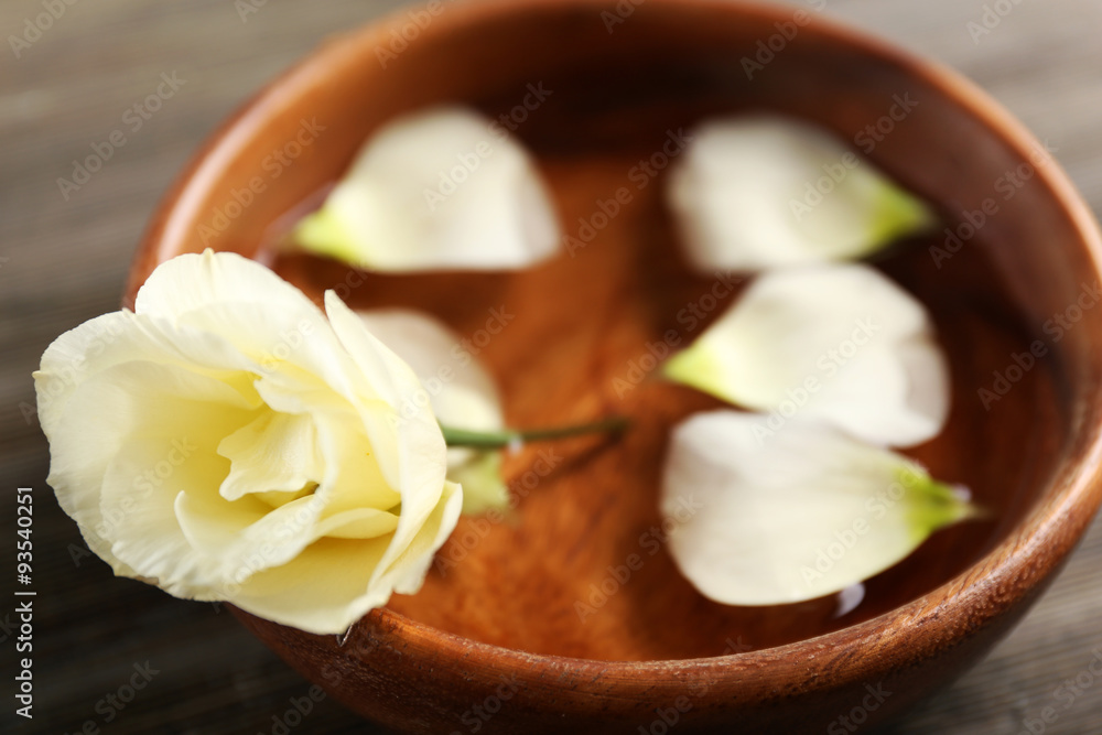 Flower petals in bowl with water on wooden background Flower petals in bowl with water on wooden background