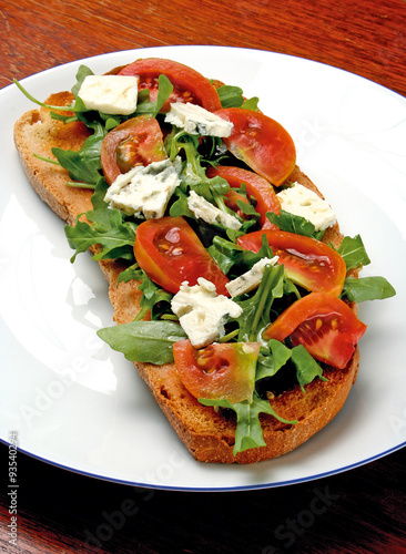 Bruschetta with tomatoes and gorgonzola cheese served with fresh rocket leaves.