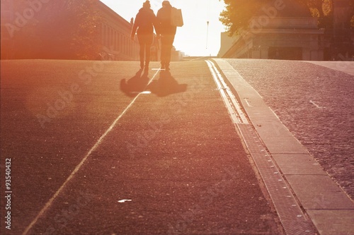 Anonymes Paar geht auf Strasse Richtung Sonnenuntergang