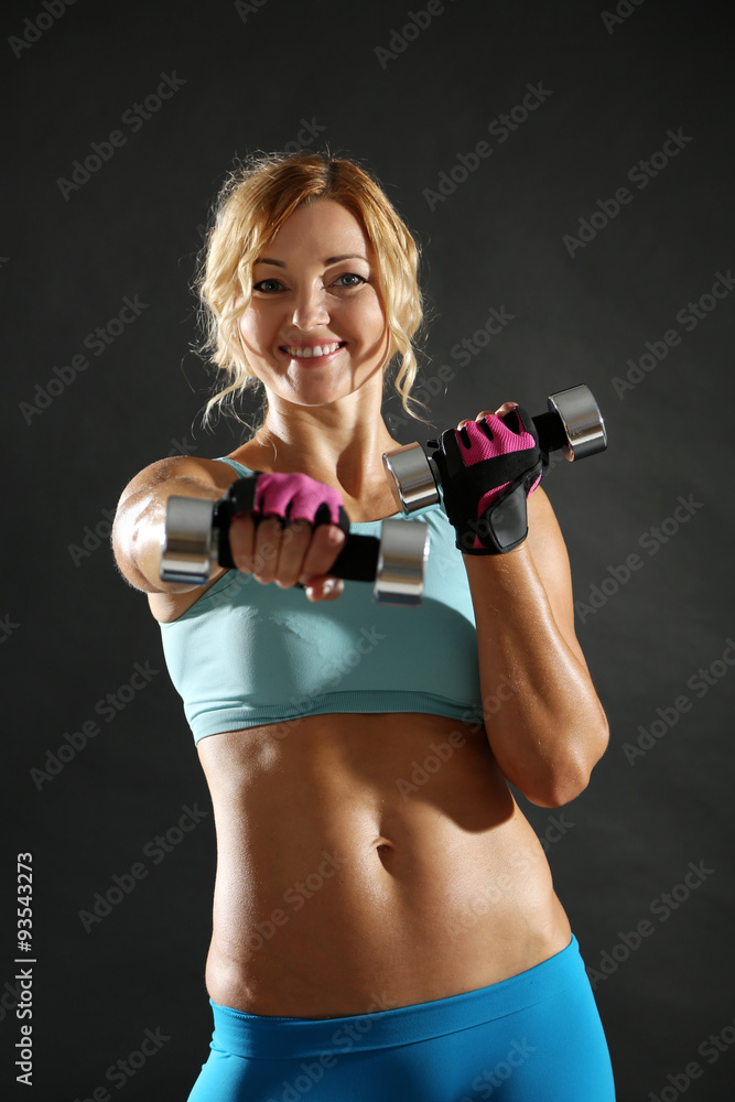 Athletic woman with dumbbells on dark background Athletic woman with dumbbells on dark background
