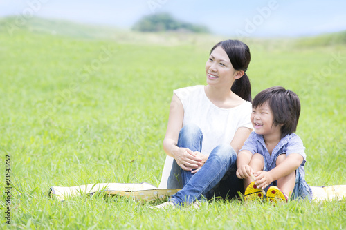 草原で電話する女性と遊ぶ子供