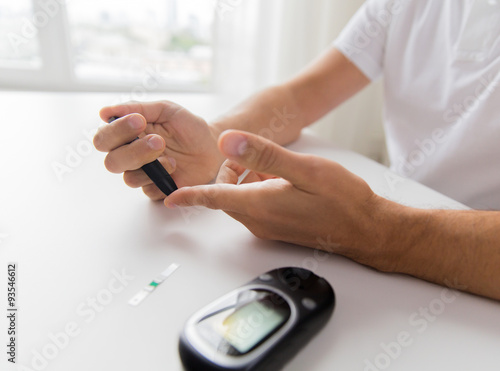 close up of man checking blood sugar by glucometer photo