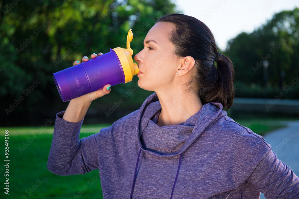 close up of fitness woman drinking water from bottle in park close up of fitness woman drinking water from bottle in park