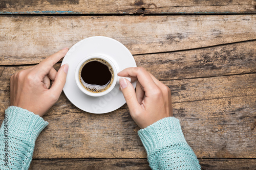 Woman's hands hold a cup of strong coffee.